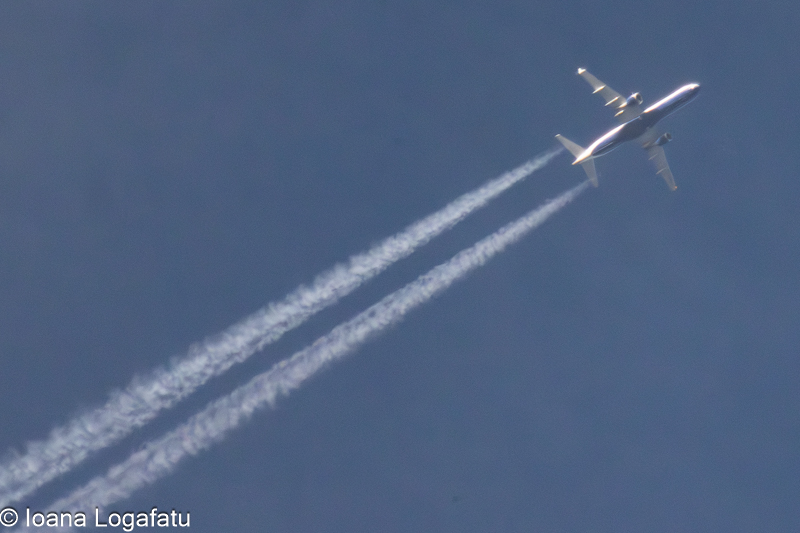 High above the clouds, a plane leaves its trail